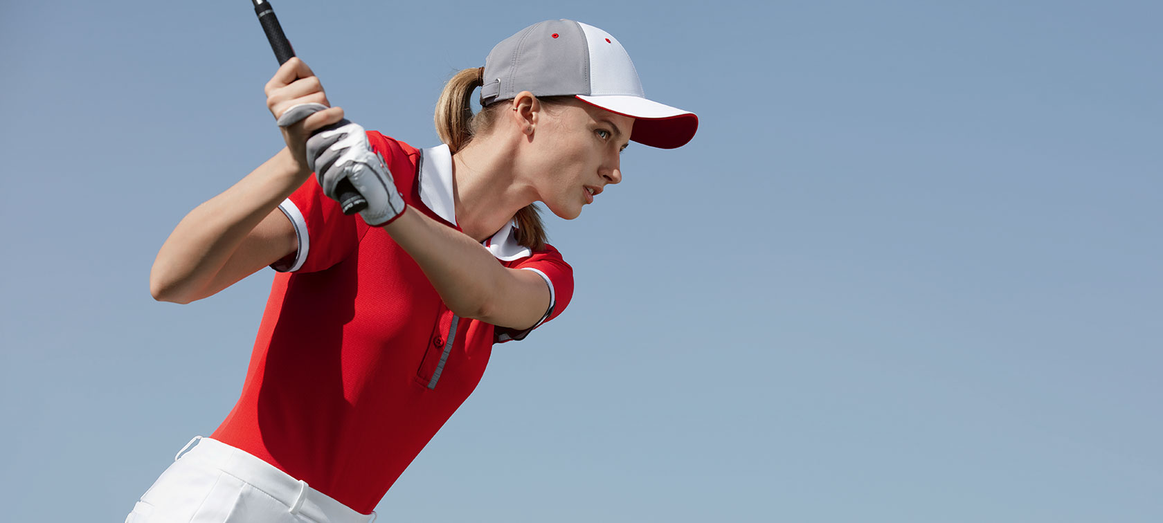 In the picture, a woman is seen wearing a BMW Golfsport Polo Shirt for Ladies and a BMW Golfsport Cap as she tees off. In the picture, a woman is seen wearing a BMW Golfsport Polo Shirt for Ladies and a BMW Golfsport Cap as she tees off.