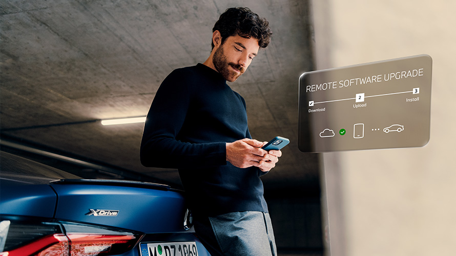 Mees nõjatub BMW tagaosa vastu ja vaatab oma nutitelefoni, tarkvara kauguuendus Tarkvara kauguuendus, mees nõjatub BMW tagaosa vastu ja vaatab oma nutitelefoni