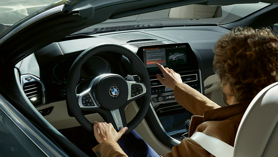 Tarkvara kauguuendus Tarkvara kauguuendus, mees istub BMW-s ja kasutab keskpaneeli ekraani
