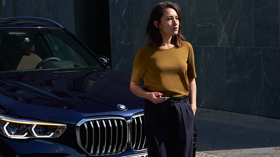 Teenindus ja rikkeabi Naine, kes istub oma BMW eesistmel ning kasutab teeninduse ja rikkeabi rakendust