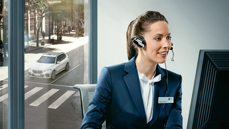Concierge teenused Concierge’i teenused: BMW töötaja, kes istub oma laua taga ja kannab peakomplekti
