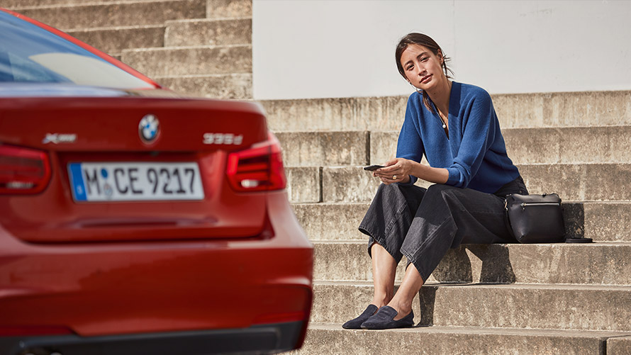 Teenindus ja rikkeabi Naine, kes istub oma BMW eesistmel ning kasutab teeninduse ja rikkeabi rakendust