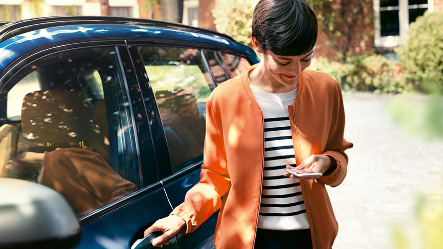 BMW Teleservices Nutitelefoniga naine seismas oma BMW ukse juures