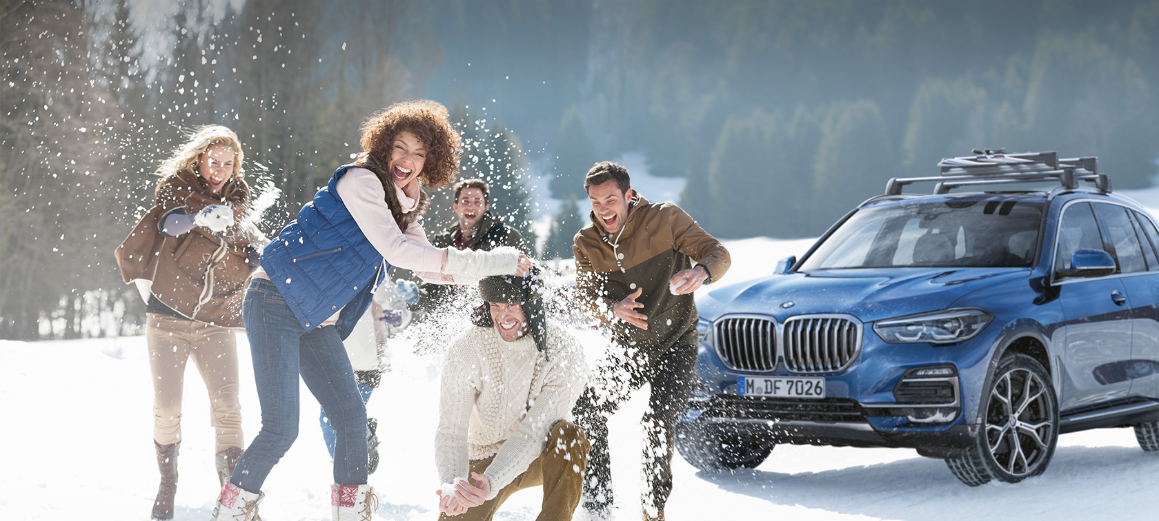 BMW originaaltarvikud ja BMW Service sügisel ja talvel Naised ja mehed naermas lumes BMW ees