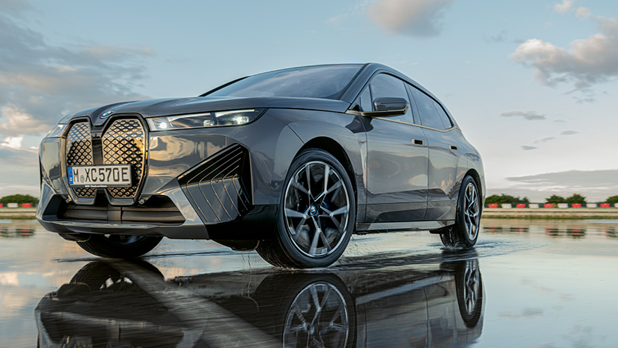 BMW veljed, BMW iX (i20) kolm neljandikku eestvaates märjal tänaval BMW veljed, BMW iX (i20) kolm neljandikku eestvaates märjal tänaval