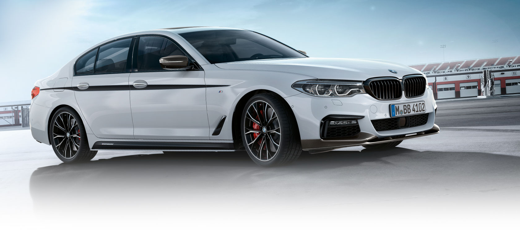 BMW 3 Series Sedan, M Performance Parts. BMW 3. seeria Sedani külgvaade parkimisplatsil koos sinise taevaga.