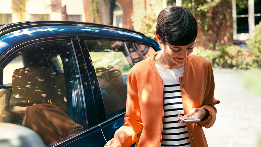 BMW suvised pakkumised BMW TeleServices BMW suvised pakkumised, BMW TeleServices, naine seisab BMW ees ja kasutab nutitelefoni