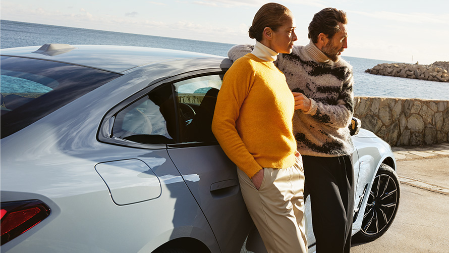 BMW Service Inclusive’i kestus ja lepinguperioodid uutele autodele BMW Service Inclusive, mees ja naine nõjatuvad rannikul BMW i4 peale